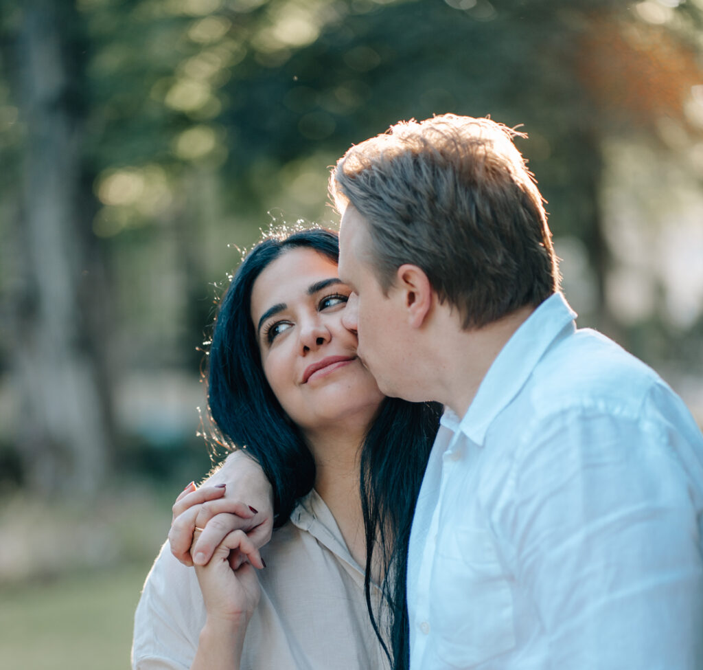Bild eines Pärchens wo der Mann die Frau auf die Wange küsst bei einem im Allgäu fotografierten Paarshooting durch eine Fotografin